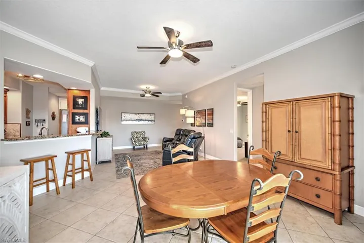 Dining area with sink, ceiling fan, light tile patterned floors, and crown molding