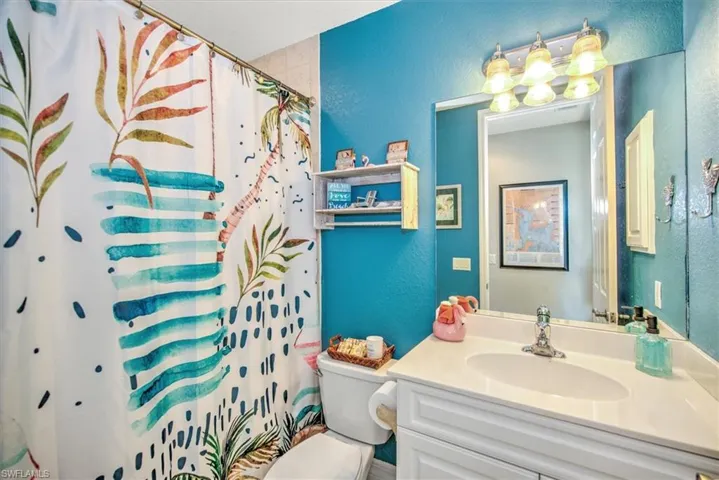 Bathroom with curtained shower, vanity, and toilet