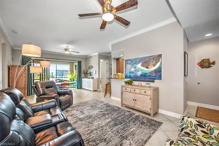 Living room with ceiling fan, crown molding, and light tile patterned floors
