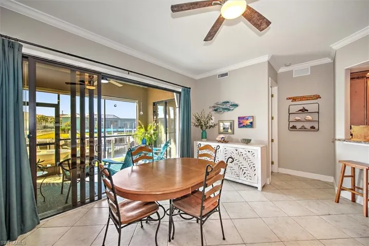 Dining space with ornamental molding, ceiling fan, and light tile patterned flooring