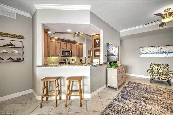 Kitchen featuring kitchen peninsula, a kitchen bar, ceiling fan, appliances with stainless steel finishes, and light tile patterned flooring
