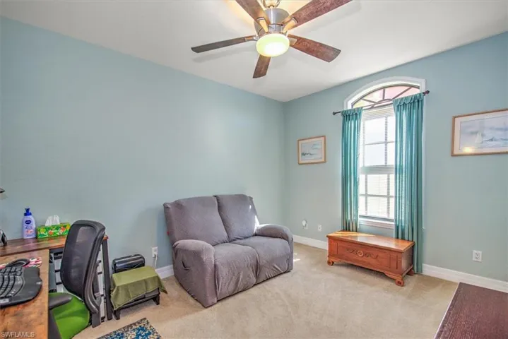 Carpeted home office featuring ceiling fan