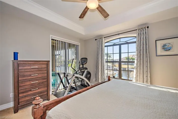 Bedroom with carpet floors, ceiling fan, and a tray ceiling