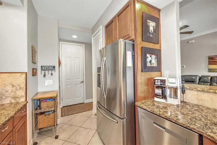Kitchen featuring stainless steel appliances, crown molding, light stone countertops, ceiling fan, and light tile patterned flooring
