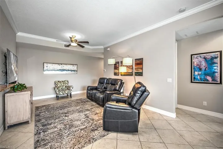 Tiled living room featuring ceiling fan, ornamental molding, and a textured ceiling