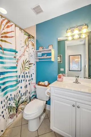 Bathroom featuring toilet, tile patterned flooring, vanity, and walk in shower