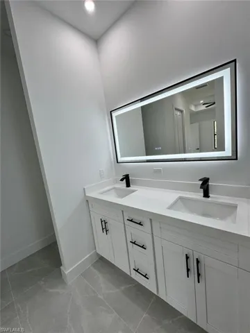 Bathroom featuring double vanity, light marble finish flooring, and recessed lighting