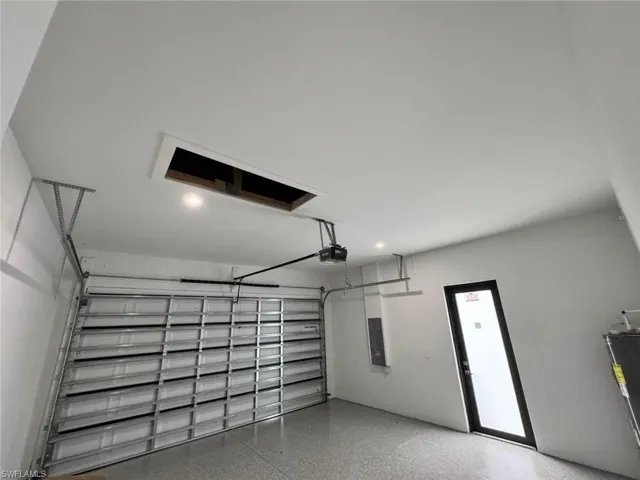 Garage with electric panel, recessed lighting, and a garage door opener