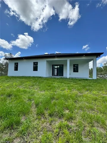 Back of house featuring stucco siding, a patio area, and a yard