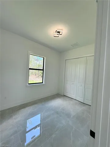 Unfurnished bedroom featuring a closet and light marble finish flooring