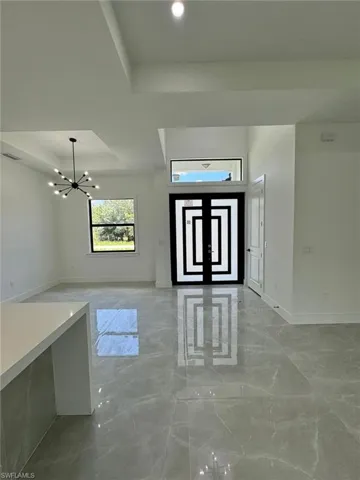 Foyer entrance featuring light marble finish flooring, a chandelier, and a tray ceiling