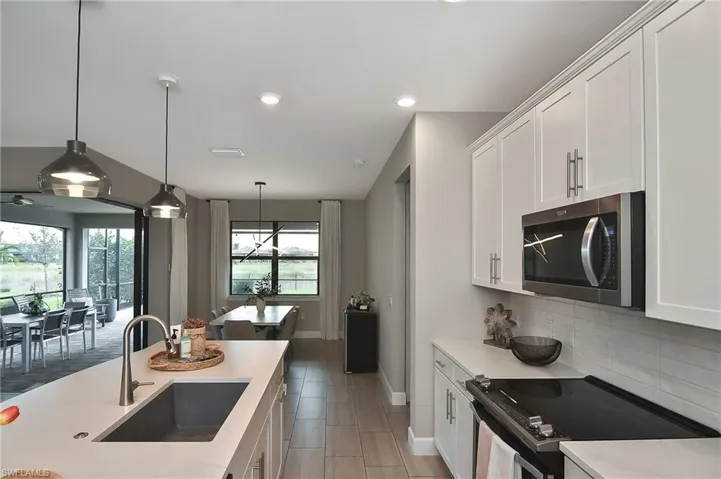 Kitchen with white cabinetry, hanging light fixtures, appliances with stainless steel finishes, and sink