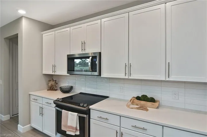 Kitchen with white cabinetry, stainless steel appliances, and tasteful backsplash