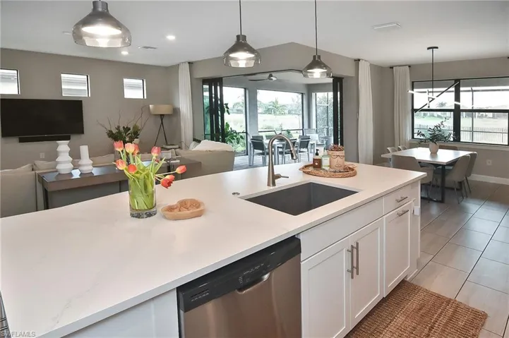 Kitchen with sink, stainless steel dishwasher, white cabinets, hanging light fixtures, and a kitchen island with sink