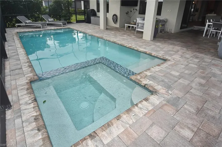 View of swimming pool featuring an in ground hot tub, glass enclosure, and a patio