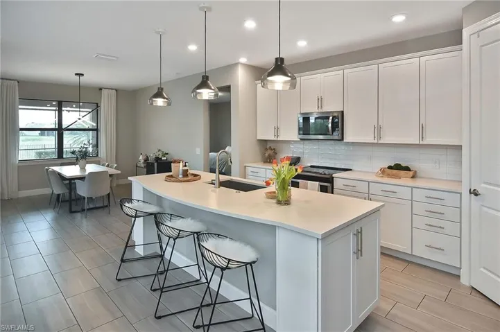Kitchen with appliances with stainless steel finishes, white cabinetry, and a center island with sink