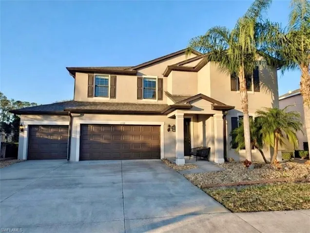 View of front facade with stucco siding, an attached garage, and concrete driveway