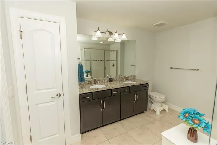 Full bathroom featuring a stall shower, double vanity, and light tile patterned flooring