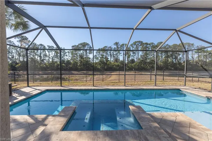 Combined pool / hot tub with a sunroom, glass enclosure, and a patio area