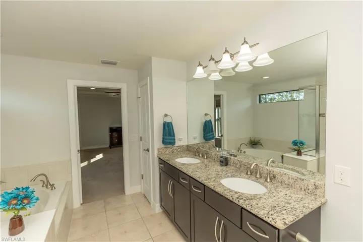 Full bath with a bath, double vanity, light tile patterned floors, and light colored carpet