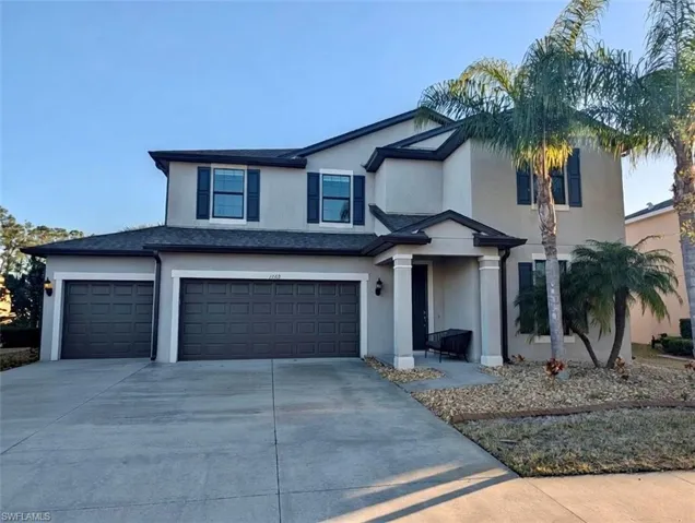 View of front of home with a garage, stucco siding, and driveway