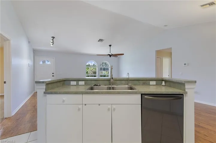 Kitchen featuring white cabinets, dishwasher, light wood-style flooring, ceiling fan, and lofted ceiling