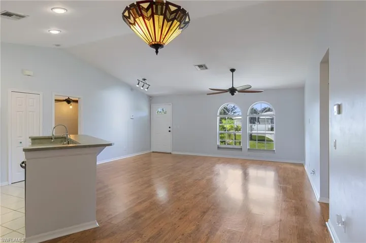 Unfurnished living room featuring vaulted ceiling, light wood-type flooring, and a ceiling fan