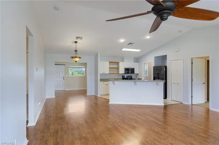 Kitchen with light wood-type flooring, ceiling fan, open shelves, a breakfast bar, and white cabinets
