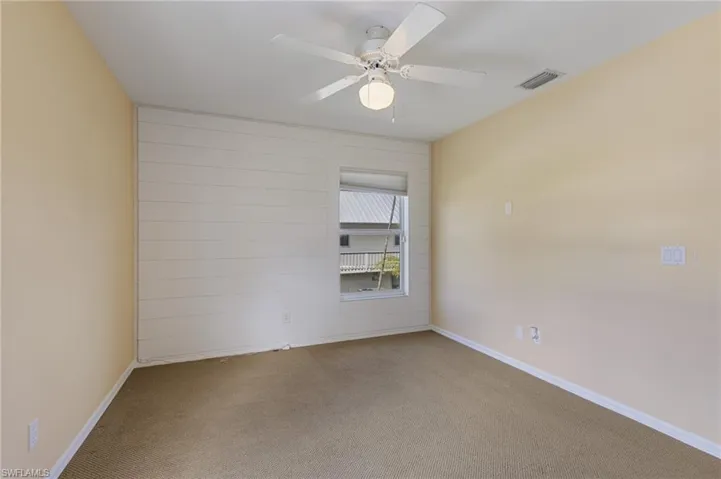 Carpeted empty room with ceiling fan and baseboards