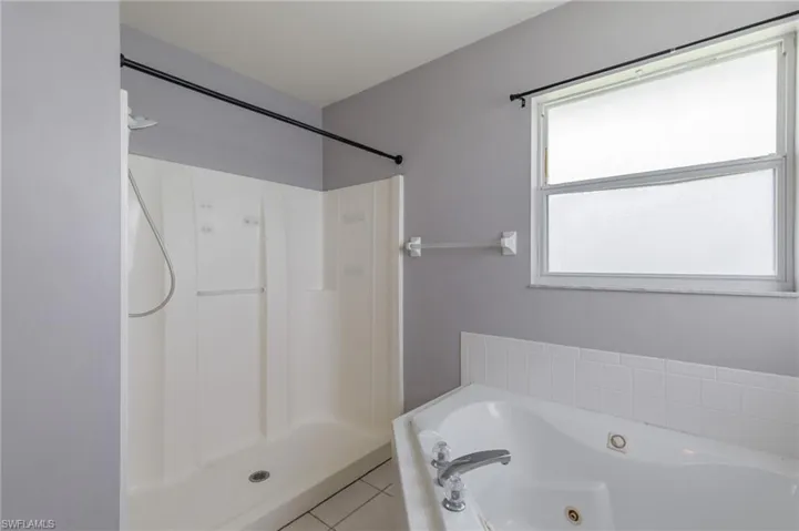 Bathroom featuring tile patterned flooring, a tub with jets, and a shower stall