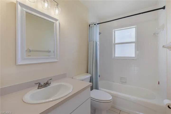 Bathroom featuring shower / bath combo with shower curtain, vanity, and light tile patterned flooring