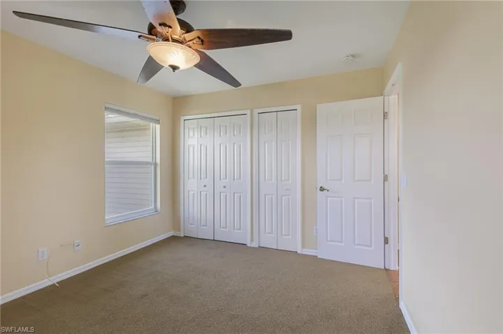 Unfurnished bedroom with multiple closets, carpet, and a ceiling fan