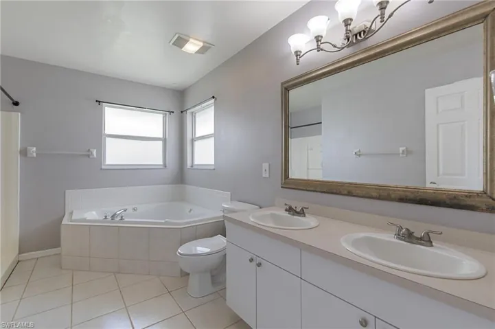 Full bath featuring light tile patterned flooring, a bath, double vanity, and a shower