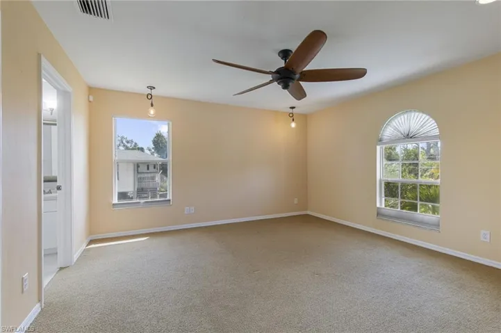 Spare room featuring light colored carpet and a ceiling fan