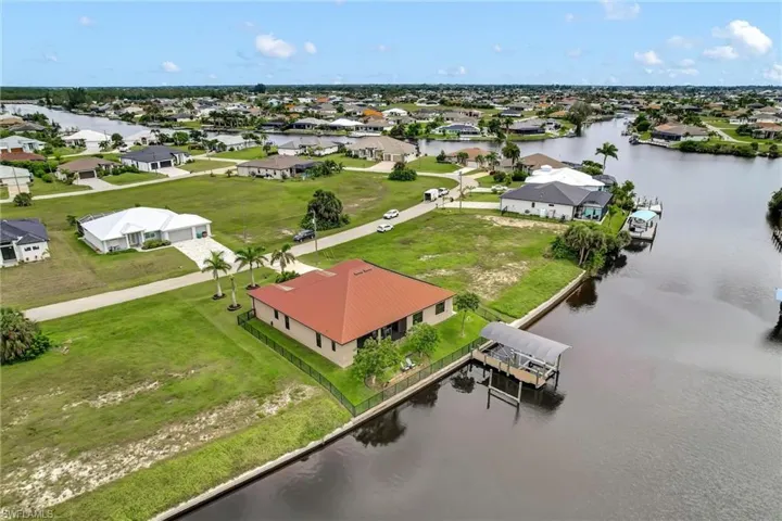 Aerial perspective of the rear of the home, boat lift and wider view of waterfront