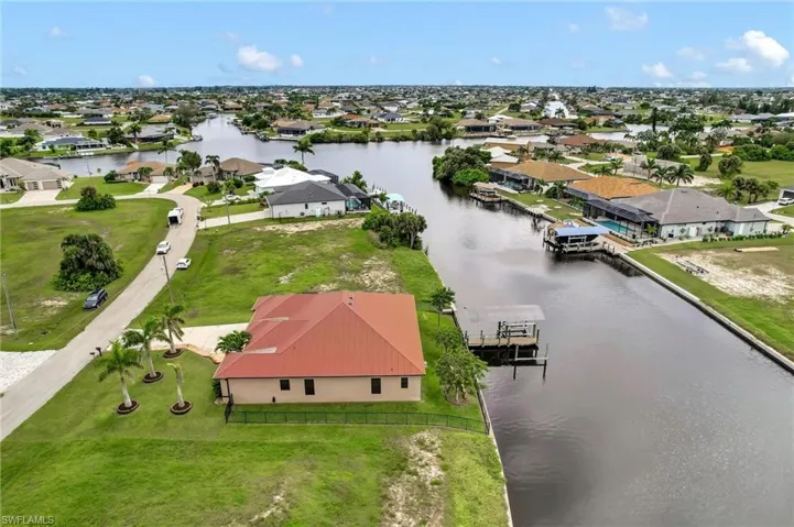 Aerial perspective of the right side of the home, boat lift and wider view of waterfront