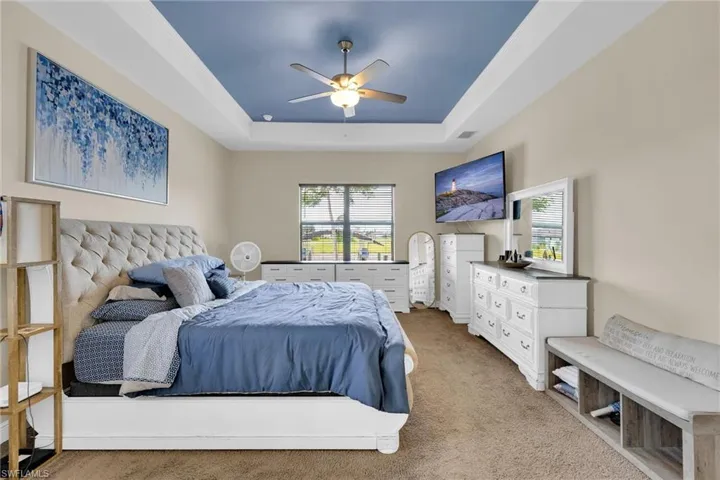 Primary Bedroom with window views of the waterfront along with high tray ceilings