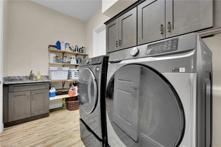 In-House Laundry Room with state of the art Washer and Dryer along with ample cabinet and storage space, and flooring throughout