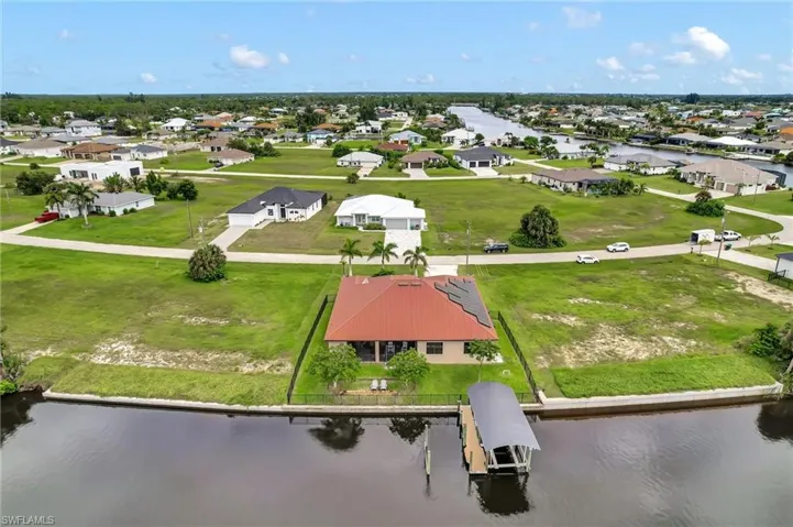 Aerial perspective of the rear of the home, boat lift and wider view of waterfront