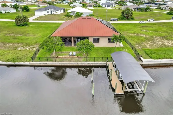 Aerial perspective of the rear of the home, boat lift and wider view of waterfront