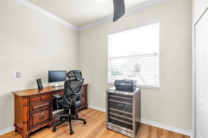 Crown molding, light wood-finish flooring, a ceiling fan, and a built-in window with blinds