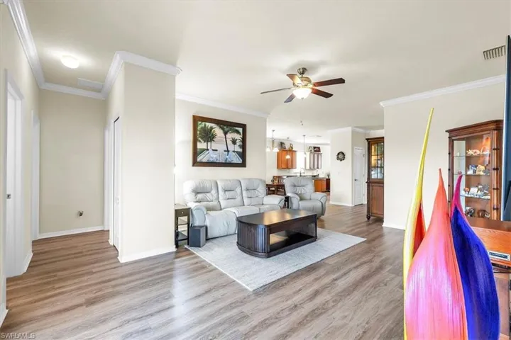 Wood-finish flooring throughout, crown molding detailing, and a ceiling fan with integrated lighting