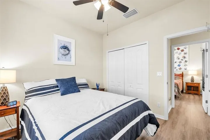 Vaulted ceiling with a ceiling fan, light-toned walls, wood-finish flooring, and a bi-fold closet