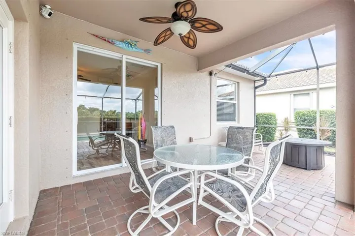 Covered patio featuring a ceiling fan, brick paver flooring, and sliding glass doors