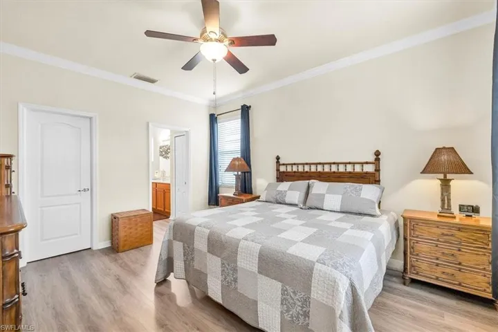 Wood-finish flooring with crown molding, ceiling fan, and window with blinds