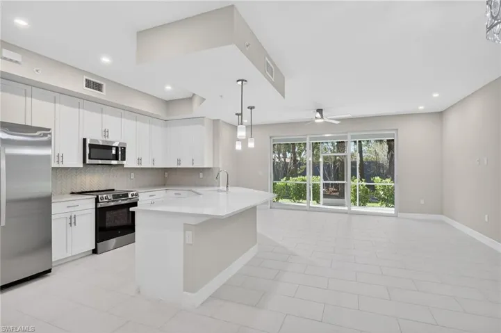 Kitchen with stainless steel appliances, white cabinetry, decorative backsplash, ceiling fan, and pendant lighting