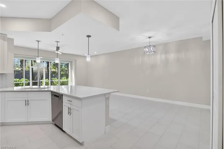 Kitchen featuring white cabinets, a peninsula, stainless steel dishwasher, a ceiling fan, and tasteful backsplash