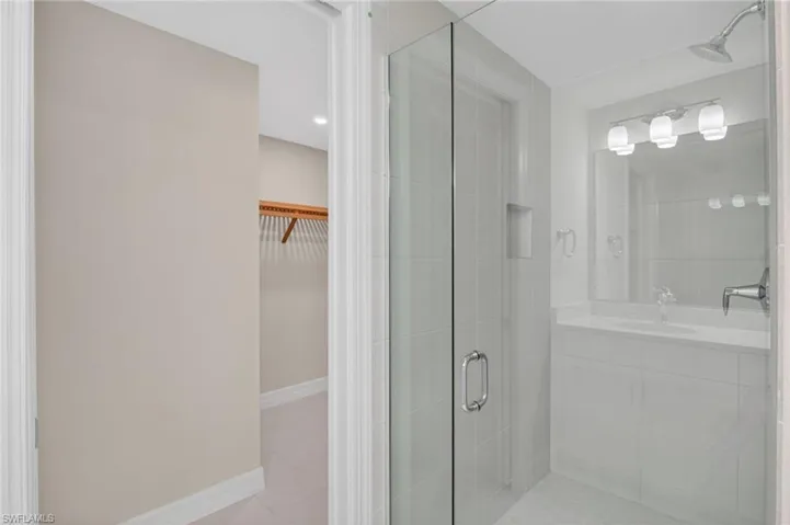 Full bathroom with a walk in closet, a shower stall, light tile patterned flooring, and vanity