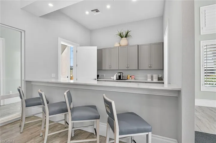 Kitchen with gray cabinetry, a kitchen bar, a peninsula, light wood-type flooring, and recessed lighting