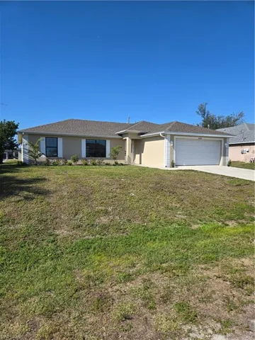 Ranch-style home featuring a garage and a front lawn
